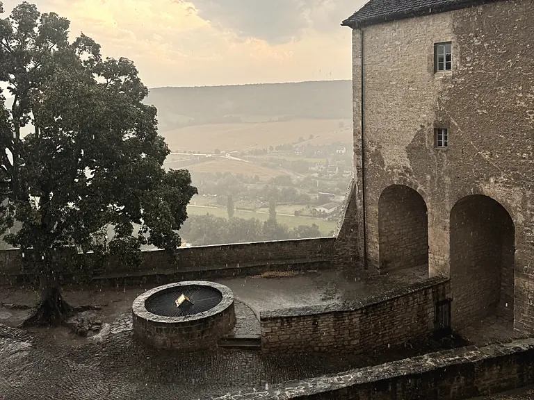 Schlosshof der Neuenburg mit Brunnen an einem Regenabend, Blick ins Tal